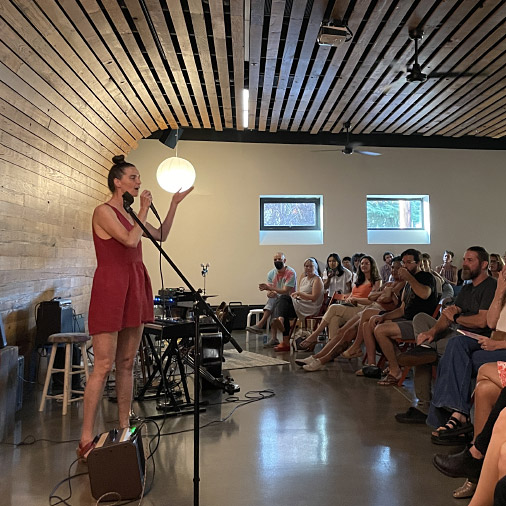 A person standing on stage in front of a seated audience.